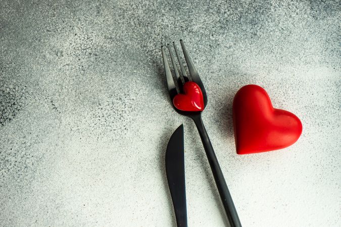 Cutlery on grey counter with red heart decorations, copy space