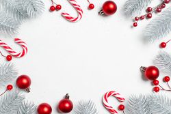 Red baubles, candy cane and frosted pine cone flat lay