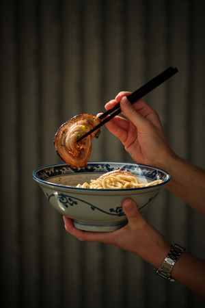 Unrecognizable person holding bowl with Asian food