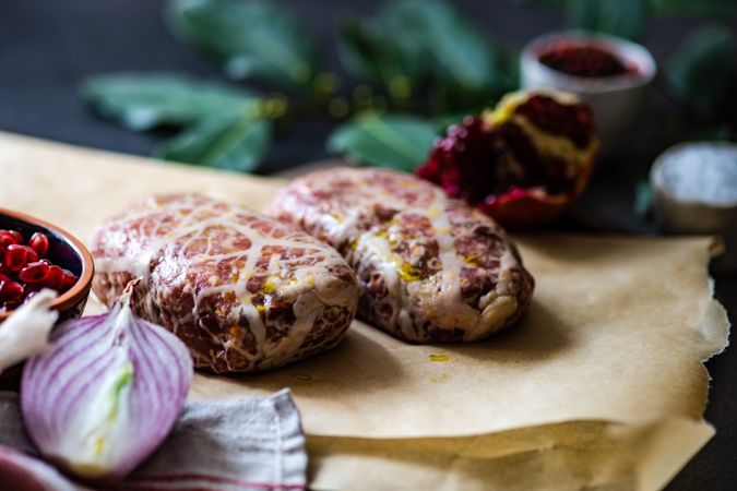 Raw abkhazura meat cutlets with pomegranate seeds, bay leaves & onions