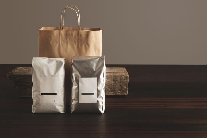 Bags of coffee beans and carrier bag presented on wooden table