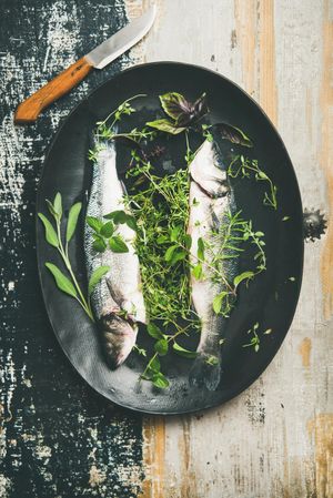 Sea bass with herbs in dark bowl, with knife
