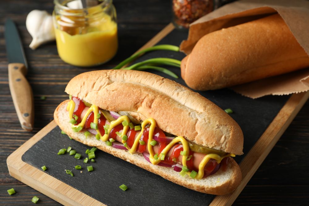 Tasty hot dog and ingredients on wooden background