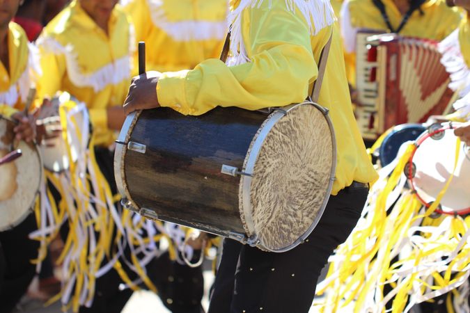Men in yellow dress shirts playing marching percussion  during traditional religious festival