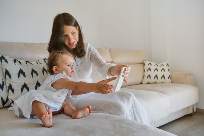 Mother and daughter using smartphone on sofa