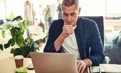 Thoughtful man working on his laptop in a bright office