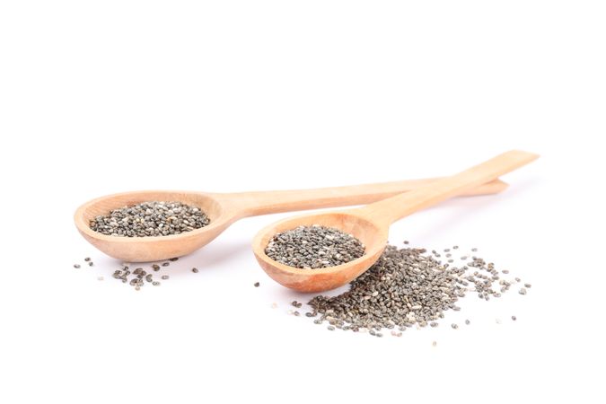Chia seeds and wooden spoons isolated on blank background