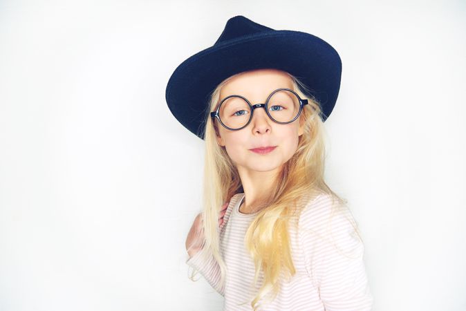 Serious blonde girl with pursed lips wearing hat and glasses