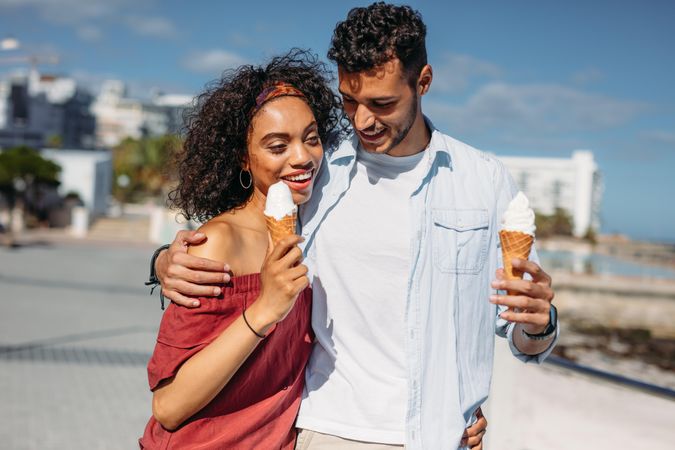 Couple in love walking on city street eating ice creams
