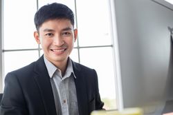 Happy male in business attire seated in front of computer screen