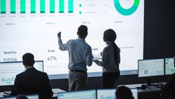 Business Team Analyzes Data on Large Screen.