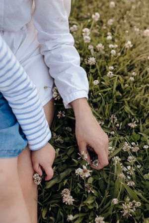 Crop mother and daughter sitting on grass