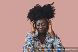Portrait of Black woman with a pensive expression and both hands to her head bxaAy0