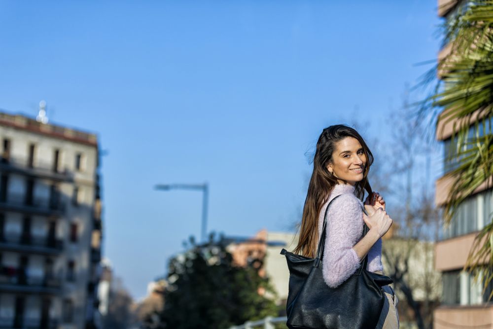 Back of smiling woman in casual wear going for a stroll in the city