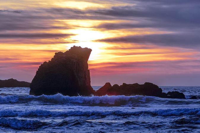 Waves cresting on rocks in the Pacific Ocean at dusk
