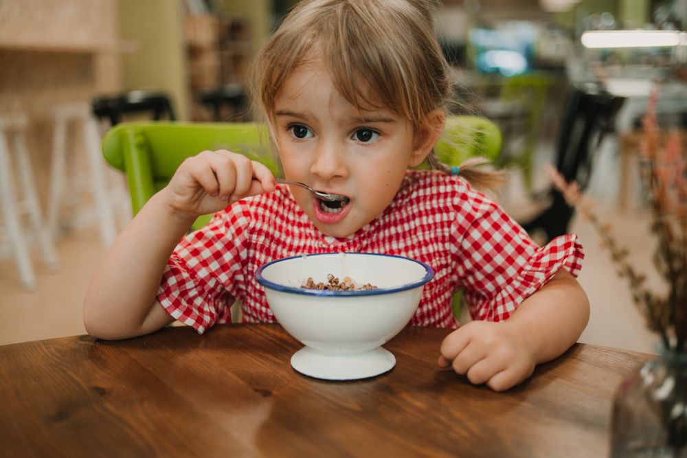 Girl eating with hand from white bowl
