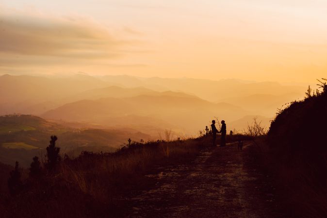 Men hugging near dog on road on hill