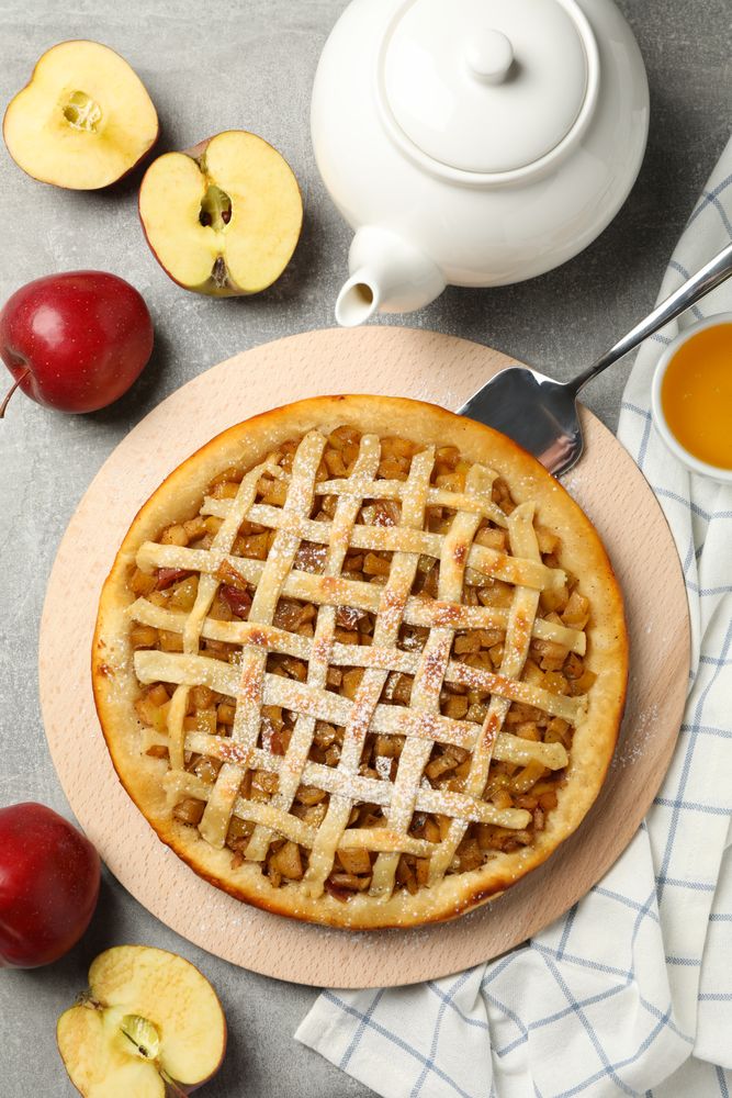 Composition with apple pie and ingredients on gray background, top view