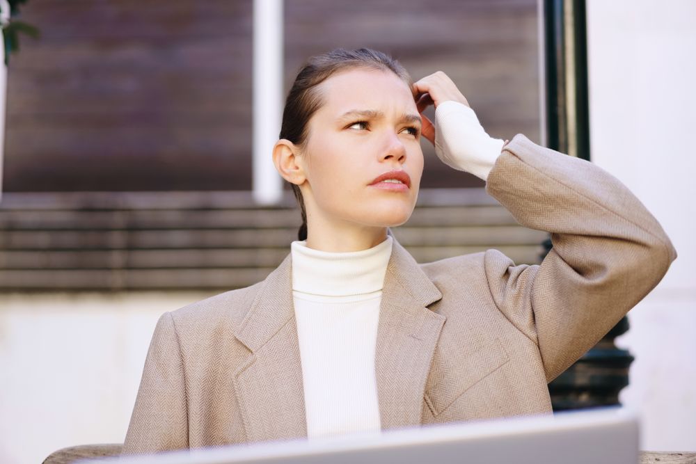 A Thoughtful Young Woman, Dressed in a Chic and Stylish Outfit, is Using a Laptop for Work Purpose
