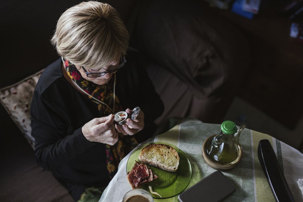 Older woman eating tablet from pill box