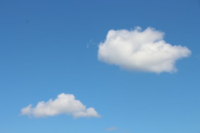 Fluffy clouds drifting in a clear blue sky during a sunny afternoon