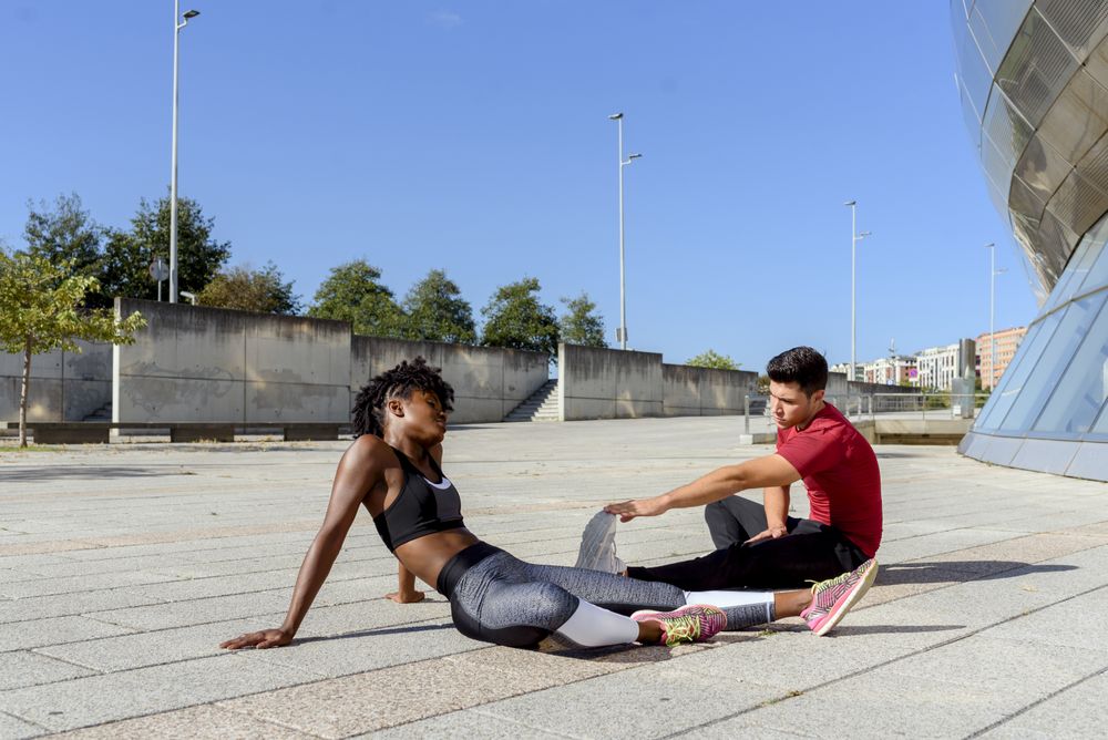 Sportive couple doing stretch exercises in city