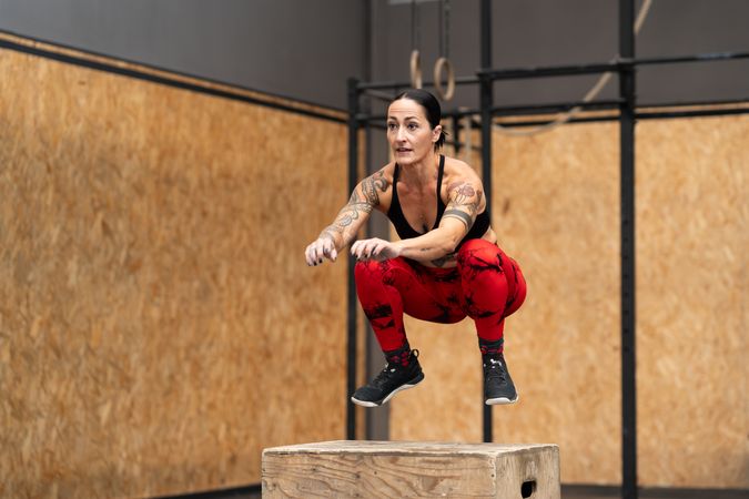Strong sporty woman jumping onto a box in a gym
