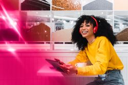 Happy woman with cup of coffee enjoying music from tablet