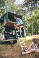 Woman ascending ladder to tent over car