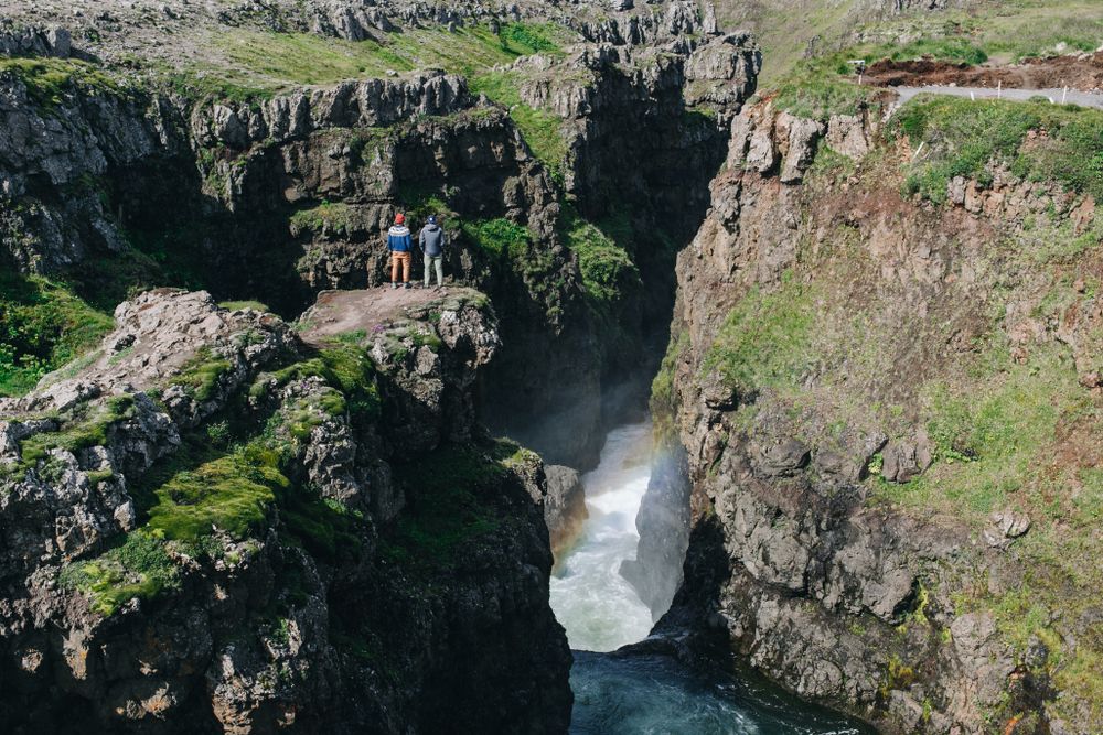 Two men on edge of cliff over waterfall, landscape