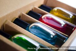 Close up of four different colored perfume bottles in a cardboard box 5qkDXj