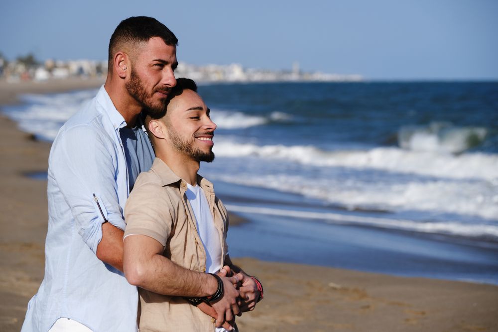 LGBTQIA couple hugging on seaside