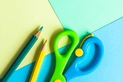 Blue & green safety scissors and pencils on paper background
