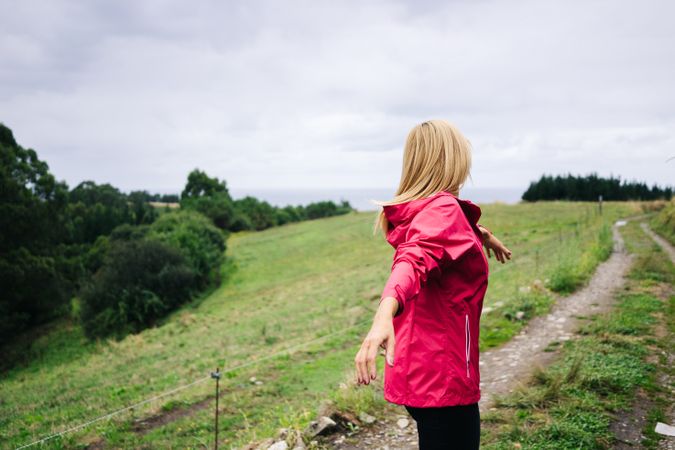 Cheerful woman enjoying countryside landscape stretching hands
