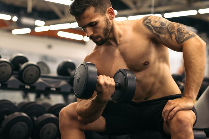 muscular man training arm with a dumbbell
