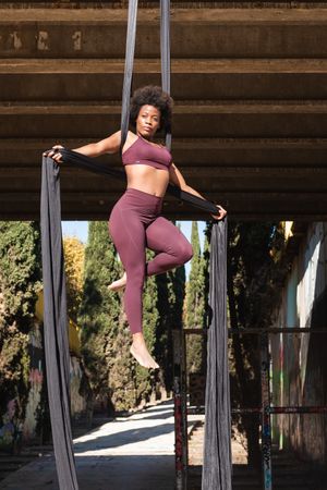 Slim woman doing yoga with aerial silks in city