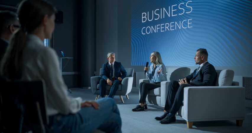 International Business Conference: Female Tech CEO Talking With Male Host In Front Of Audience Of Diverse Attendees.