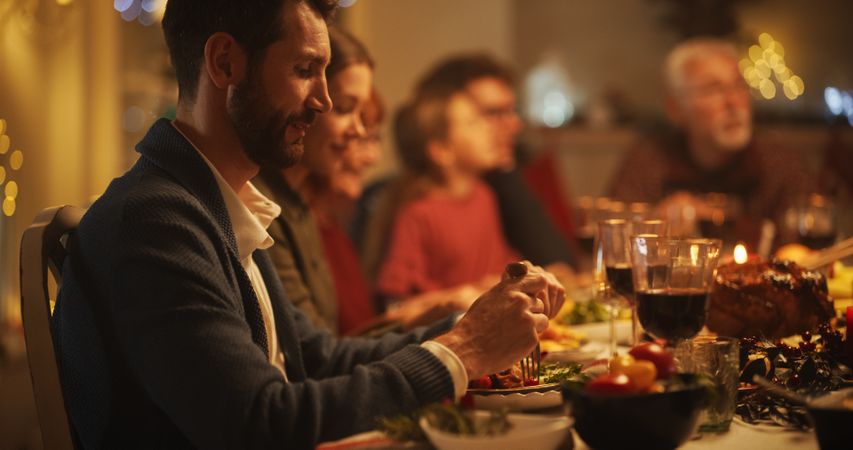Portrait of Older and Younger Men and Women Sitting Together at a Cozy Christmas Dinner Celebration at Home.