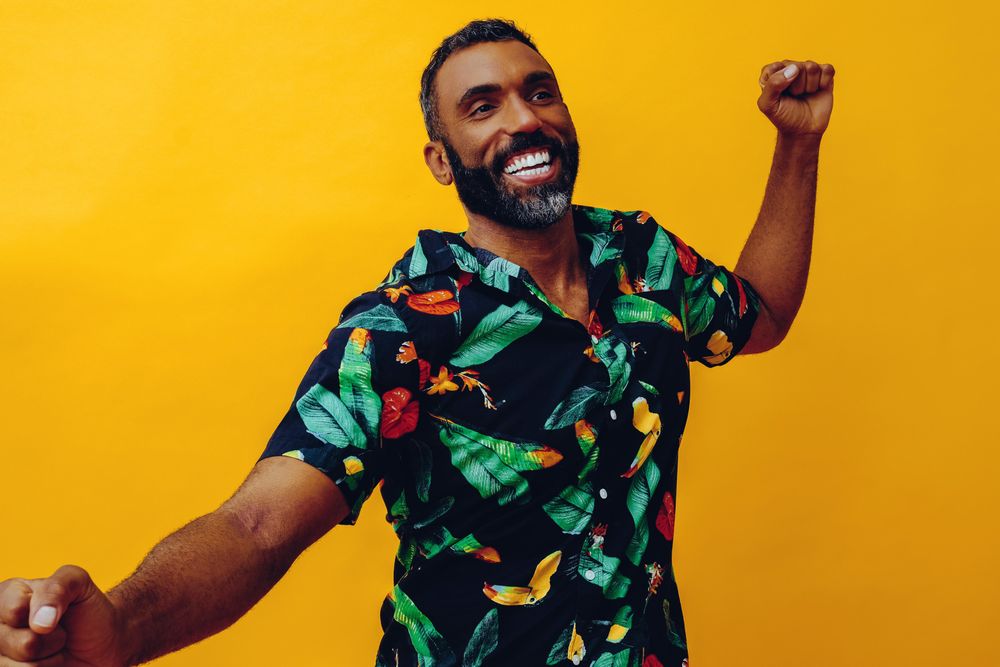Smiling male dancing in brightly patterned shirt, copy space