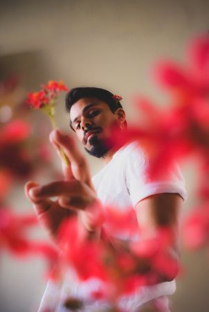 Portrait of man holding red flower against light background