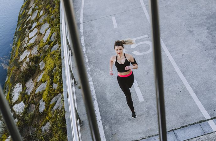 Young woman running on embankment near water