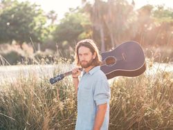 Hipster man in jungle with guitar