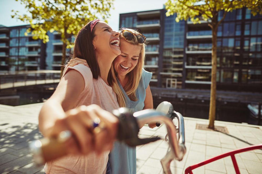 Two close female friends happily walking along the waterfront, close up
