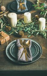 Festival holiday table setting on wooden table, with gold ornaments and branches