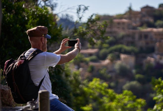 Male tourist taking picture of old town on smartphone