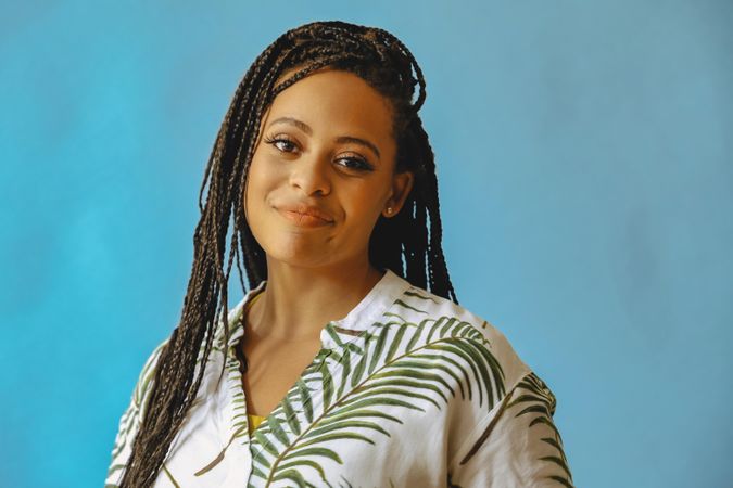 Portrait of confident smiling female with long braided hair in printed leaf shirt, copy space