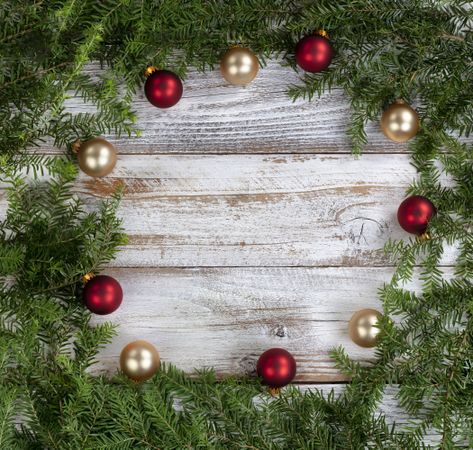 Real fir wreath with gold and red ball ornaments on rustic wood for the Christmas or New Year holiday background