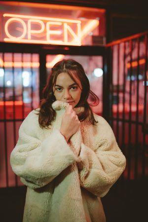 Attractive woman in fur coat standing outdoors at night