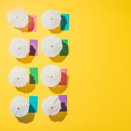 Aerial view of sun umbrellas and multicolored towels in rows on yellow