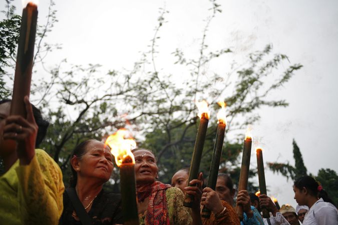 Indonesian women with torches with lit flames marches during Nyepi day on an overcast day